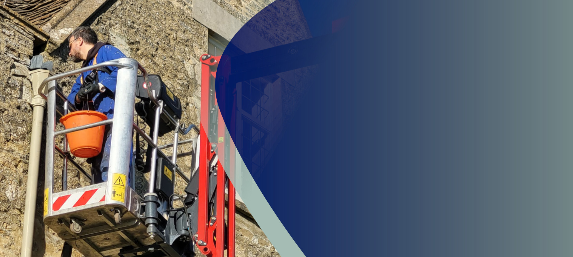 A handyman in a Cherry Picker inspecting gutters of a country house in the Cotswolds