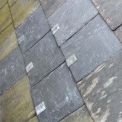 A slate roof with lead strips holding in replacement tiles following a repair. 